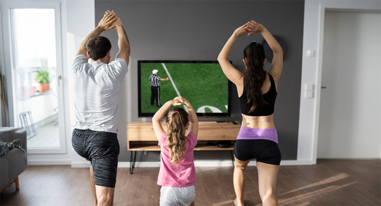 Family exercising while watching a football game on television