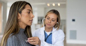 Physician listening to a young female patient's heart with a stethoscope to check for heart disease