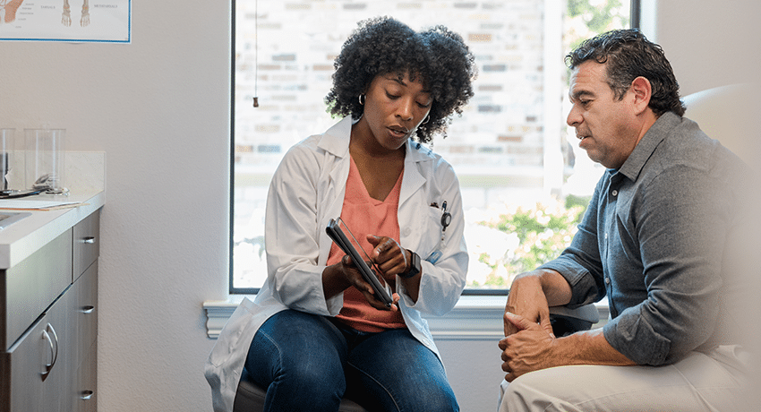 doctor showing information on tablet to patient in medical office.